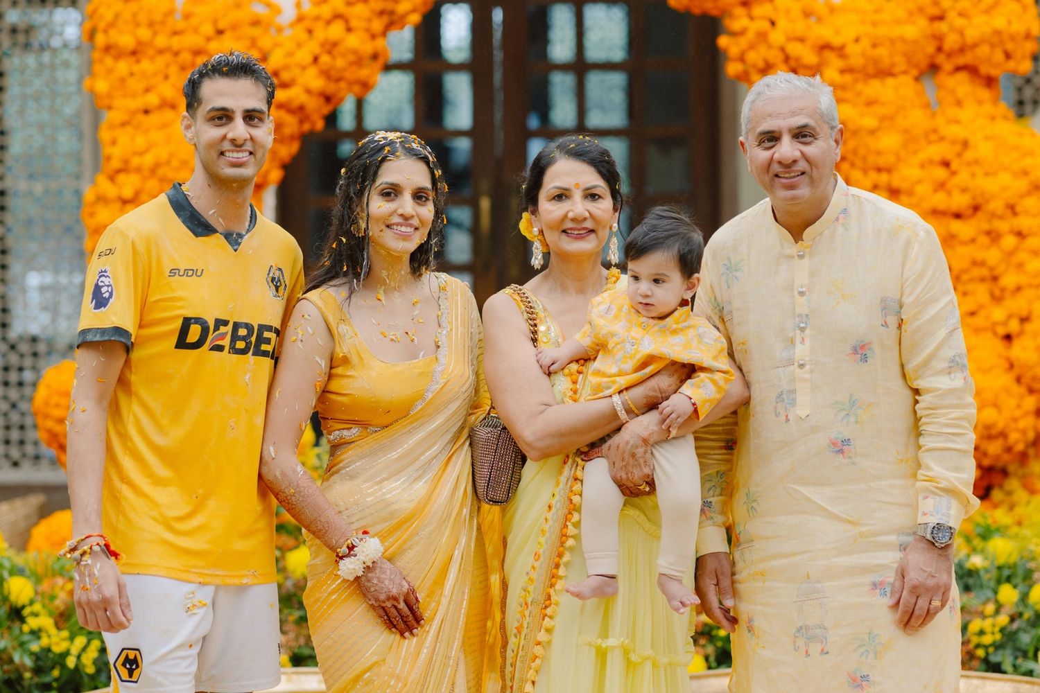 Family group photo with yellow marigold decorations in the background.