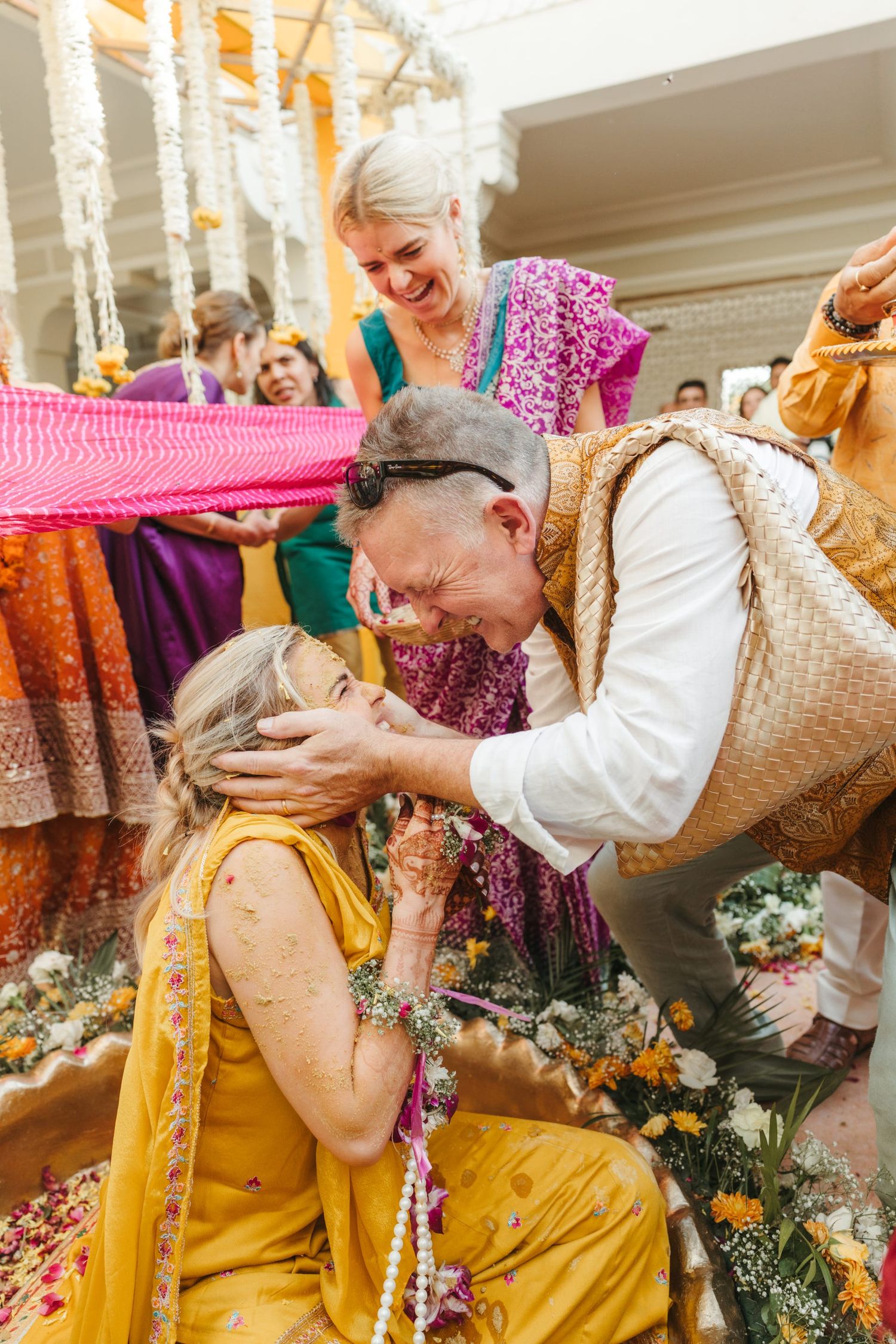 Joyful celebration with yellow attire and flower garlands during a traditional Indian Haldi ceremony.