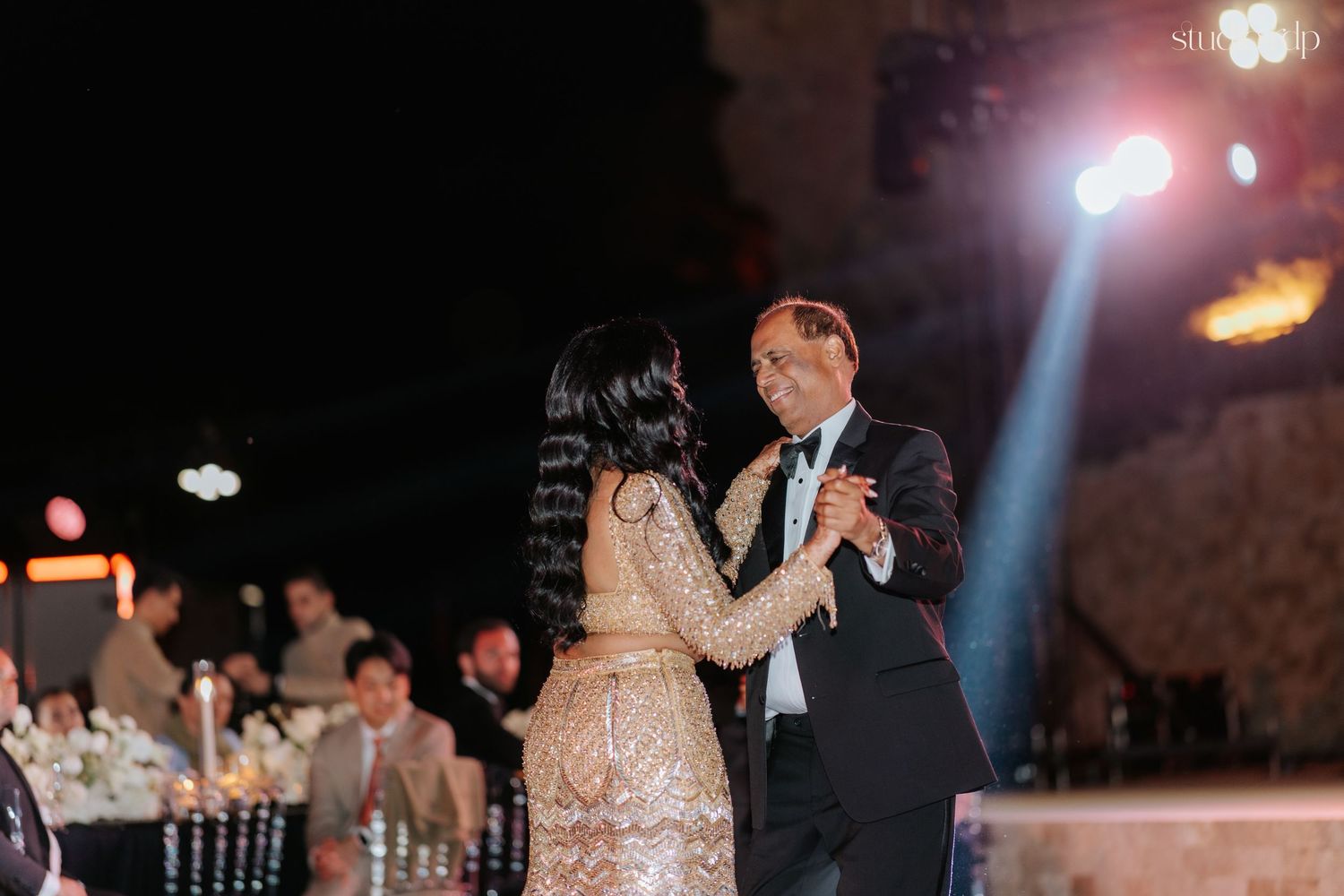 Bride and groom share a romantic first dance at an elegant outdoor wedding reception at night.
