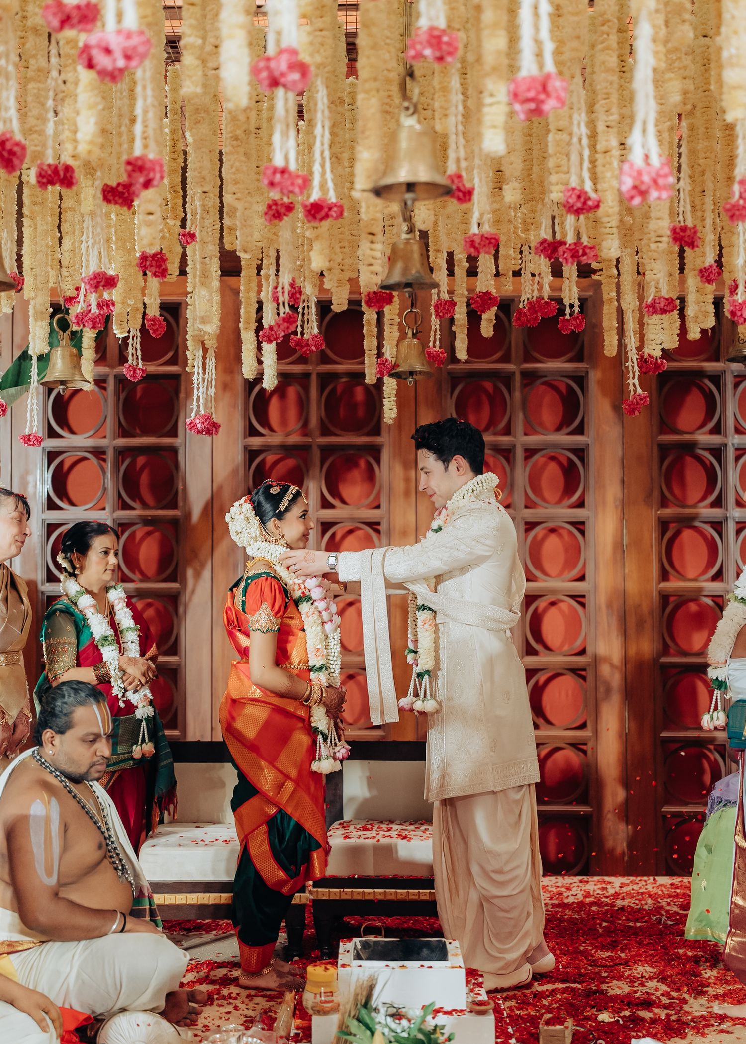 Wedding ceremony space decorated with hanging pink flowers and ornate red wall details.