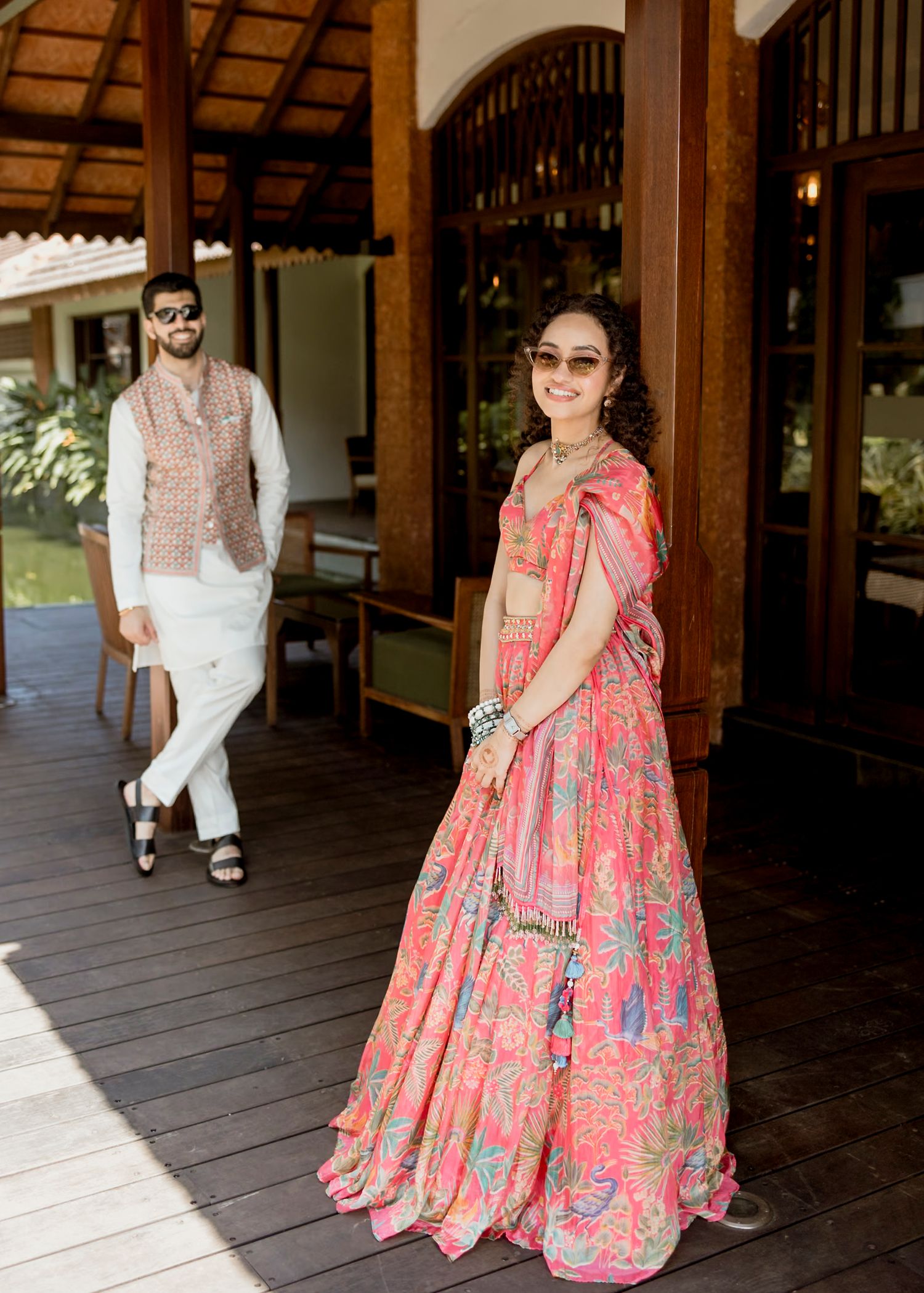Traditional pink and silver embroidered lehenga shown in a wooden corridor with natural lighting.