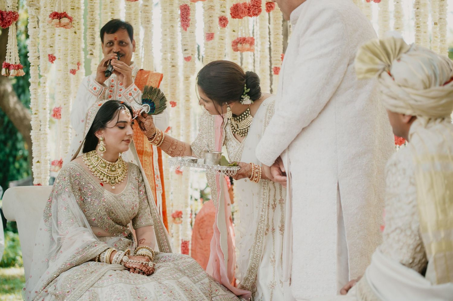Traditional Indian wedding ceremony unfolds with decorative floral mandap and elegant attire in soft pastel colors.
