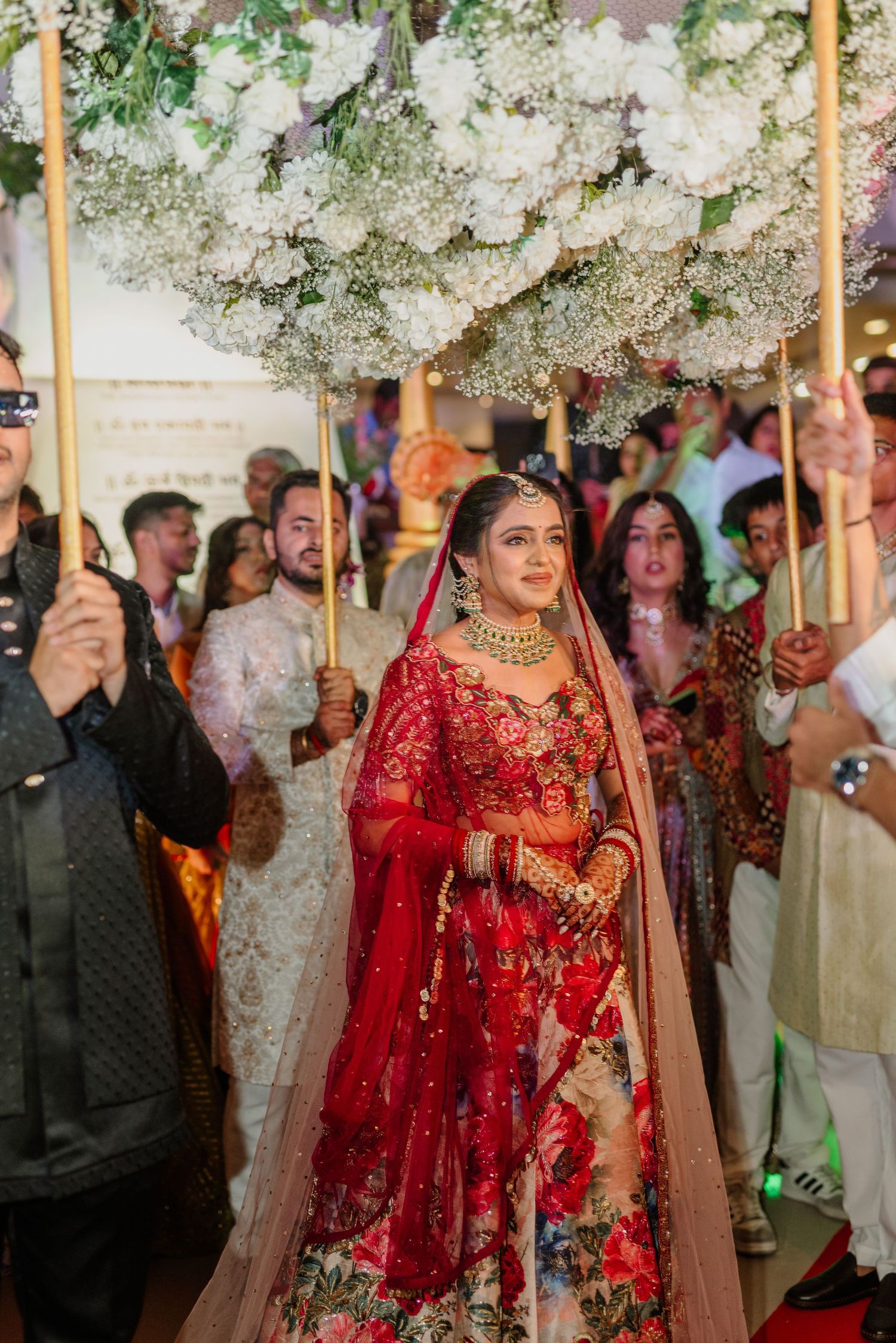 A joyous wedding celebration showing guests and decorators with white floral arrangements under a canopy.