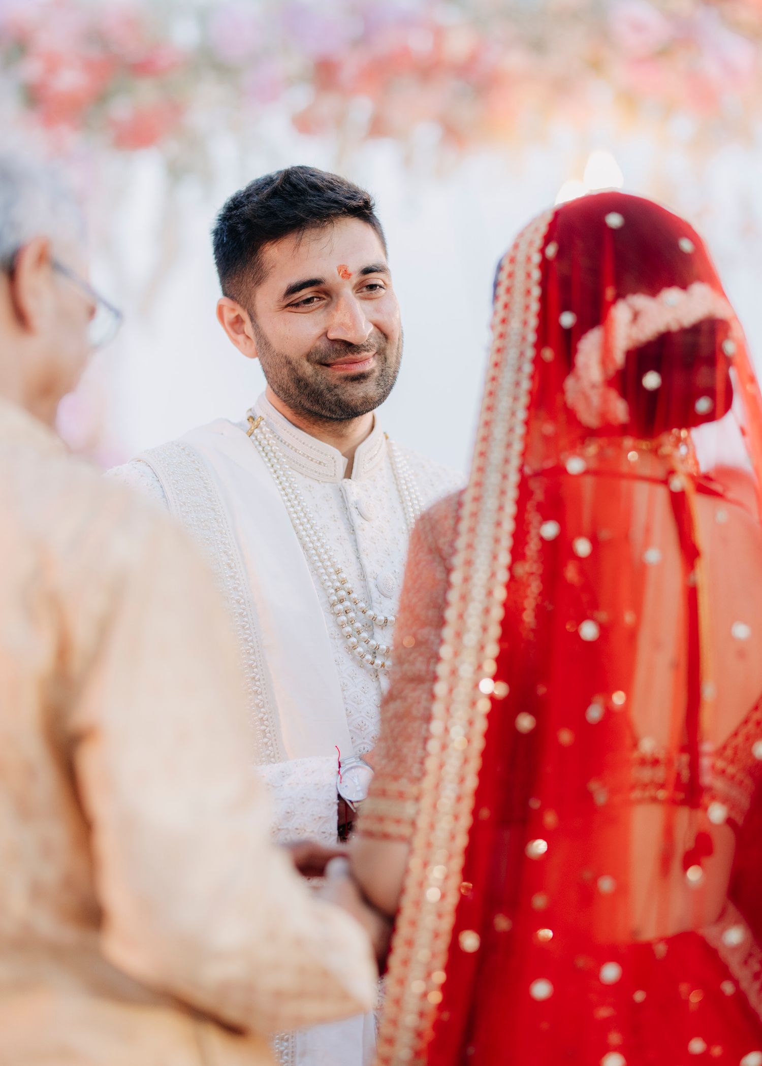 A couple shares a tender moment during their traditional Indian wedding ceremony with red and white attire.