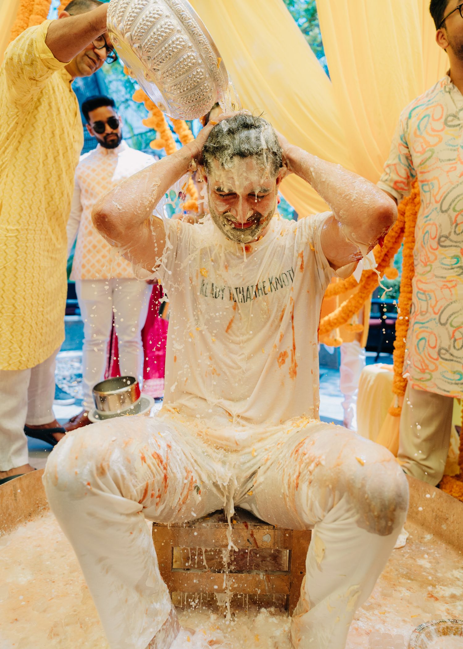 Traditional Indian Haldi ceremony participants covered in yellow turmeric paste celebrate with joyful expressions.