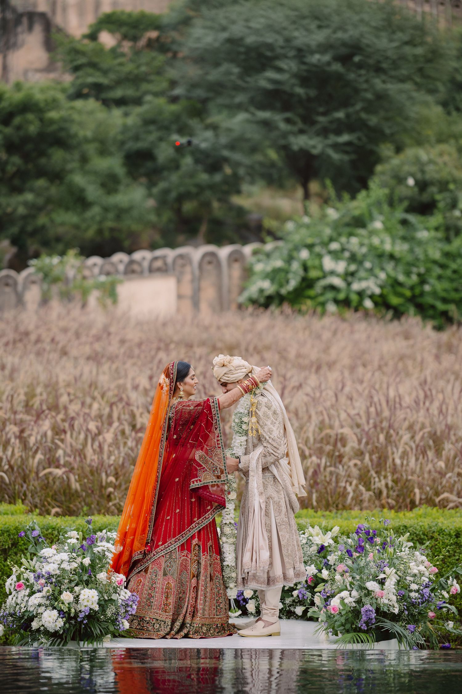 Indian wedding ceremony setup with floral arrangements and natural wheat field backdrop.