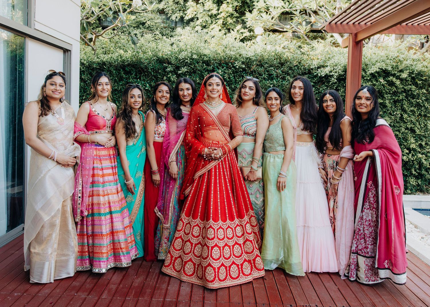 A group in colorful traditional South Asian attire poses together at an outdoor event.