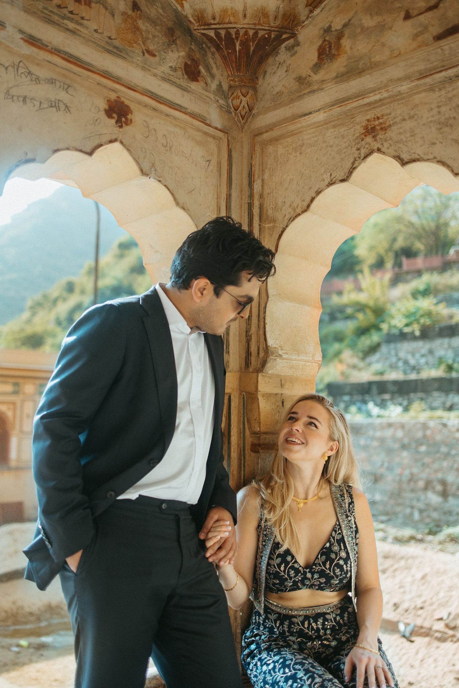 A couple shares a joyful moment under decorative arches at a historic palace.