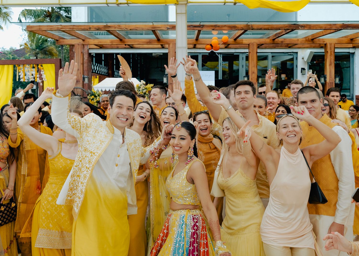 Wedding party guests celebrating in yellow and gold traditional Indian outfits.
