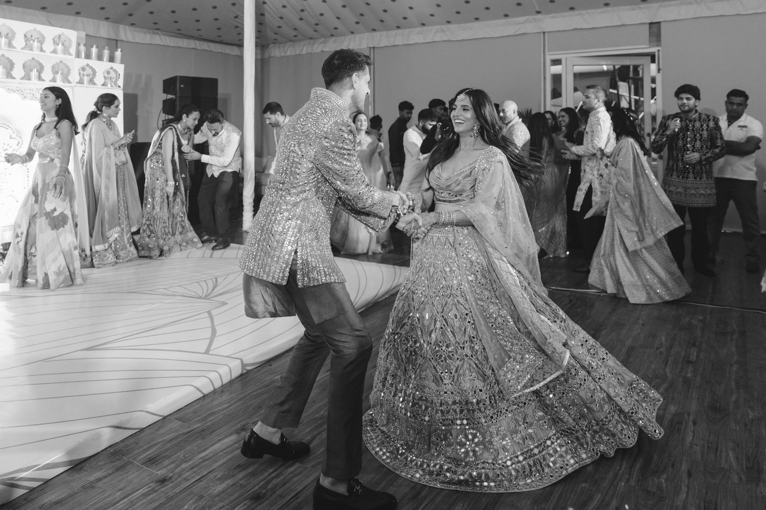 A couple dances together at their wedding reception in sparkling Indian formal wear.