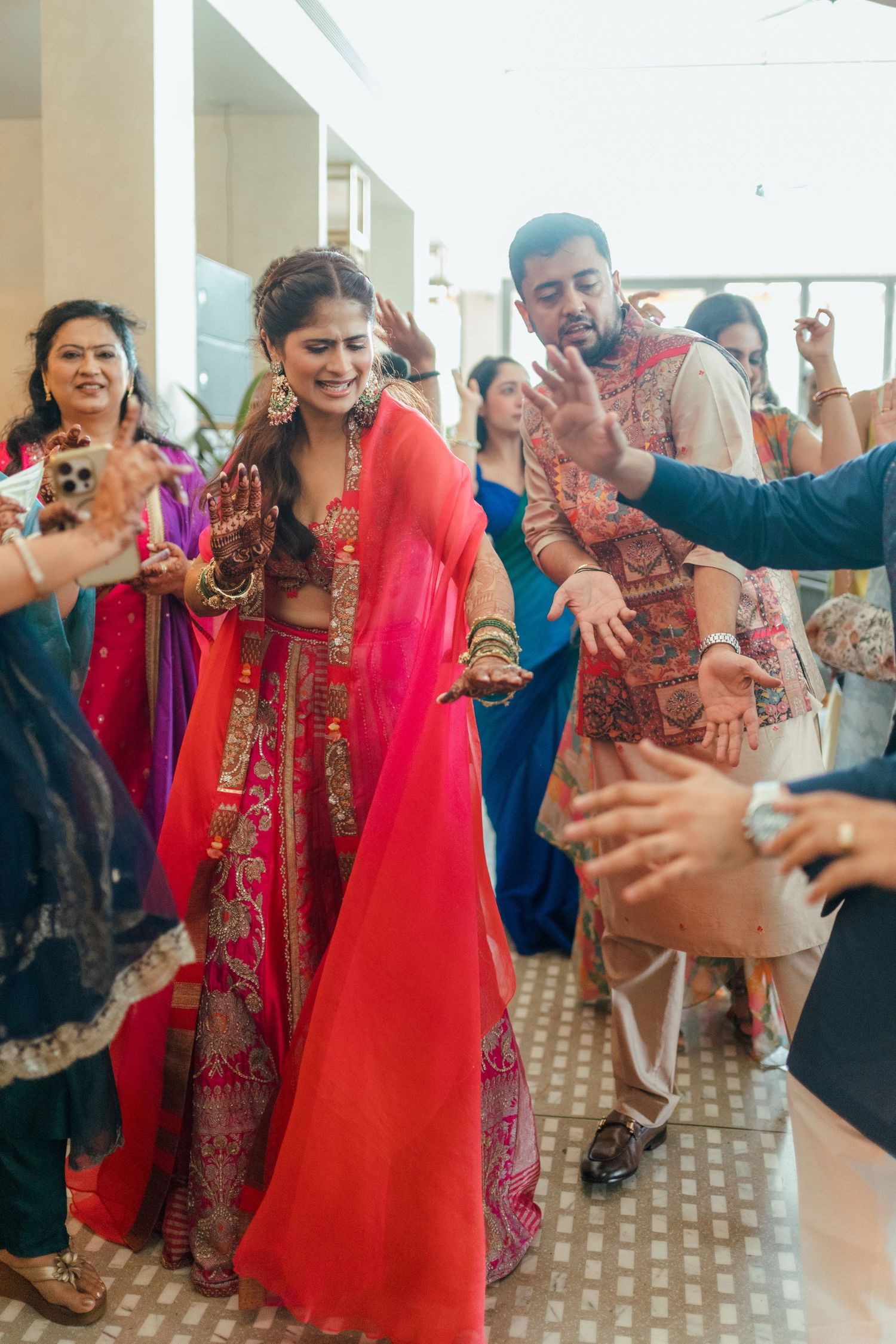 Bride and groom dancing joyfully in traditional Indian wedding attire at a vibrant Sangeet ceremony.