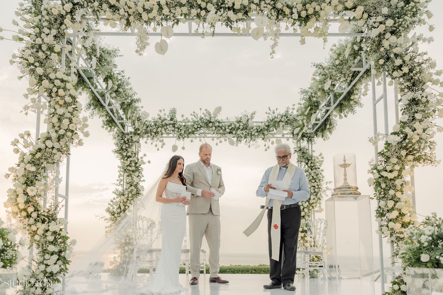 A beautiful wedding arch decorated with white flowers and greenery against a light backdrop.