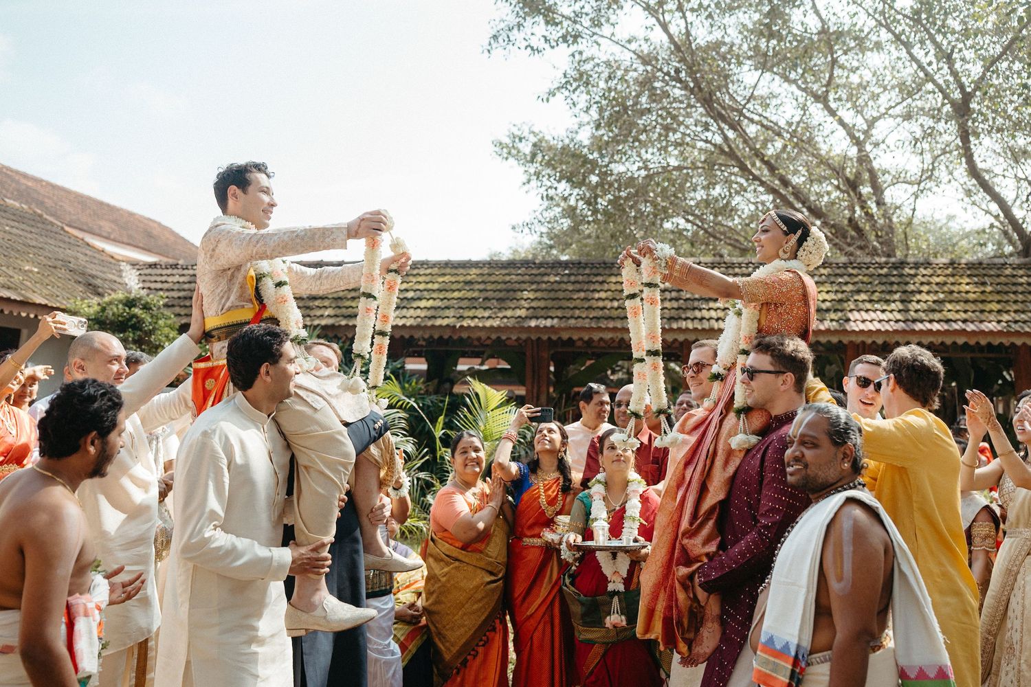 Joyful wedding celebration with guests dancing and celebrating outdoors.