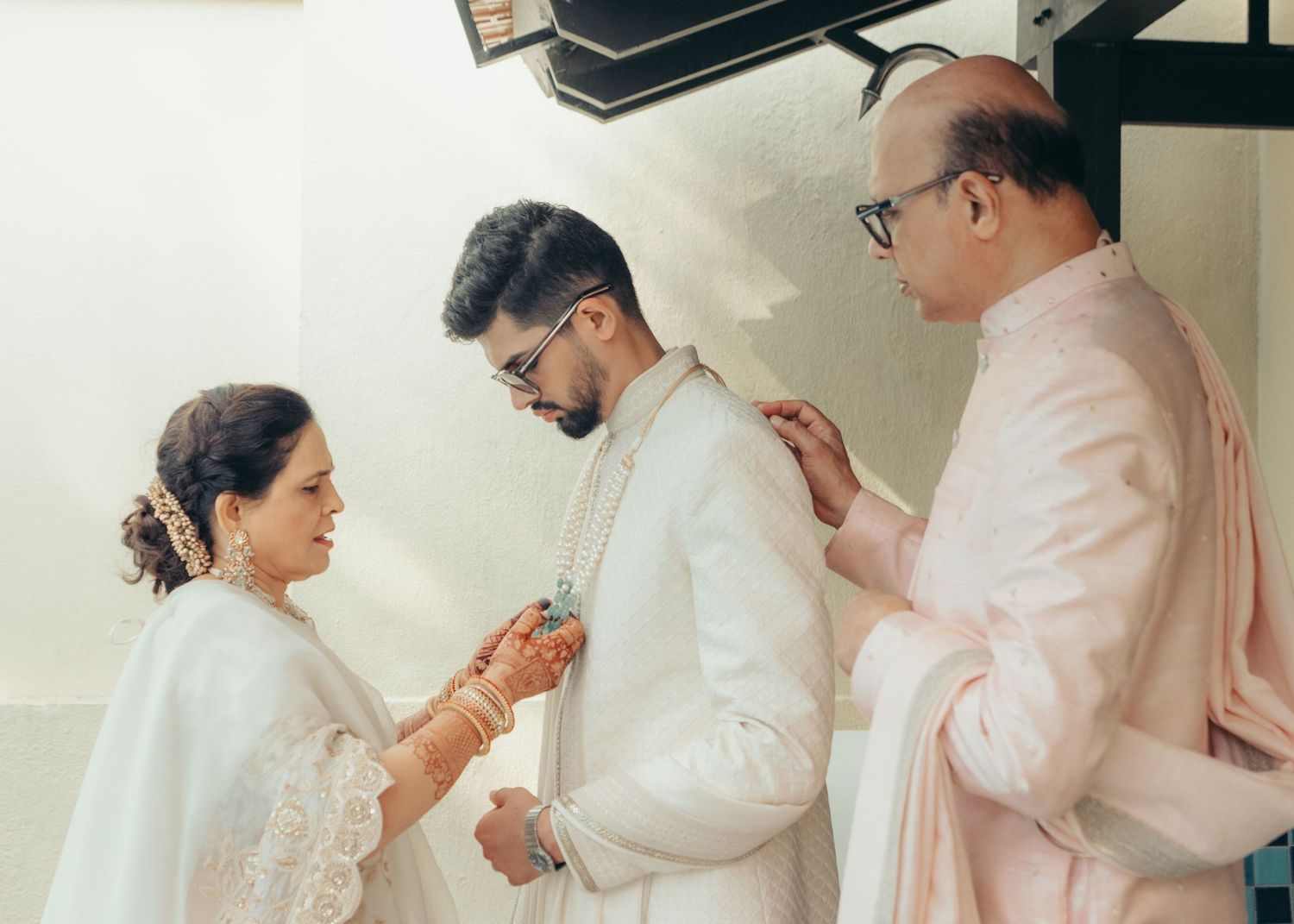 Three people in light-colored clothing stand close together during a traditional ritual or ceremony.