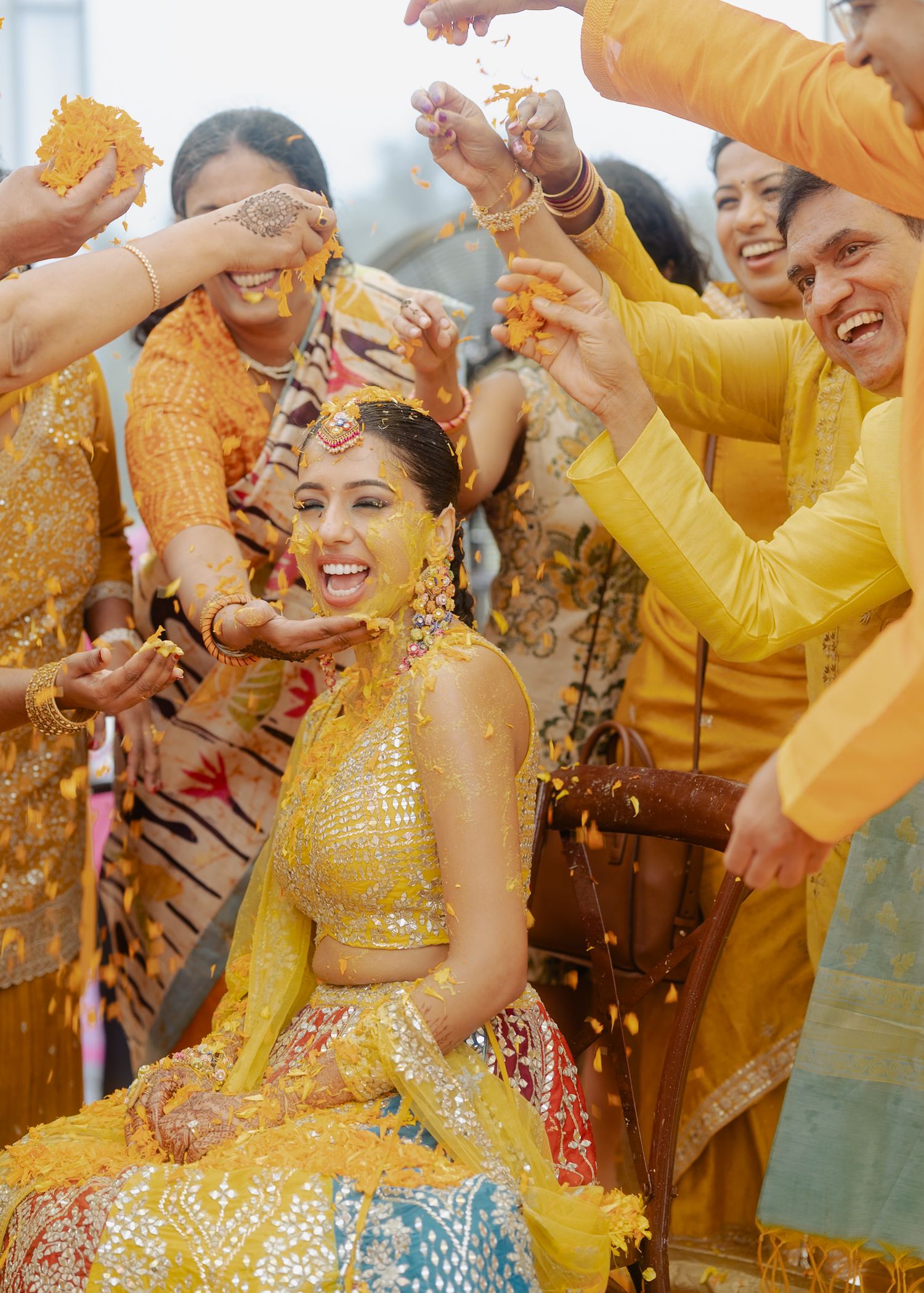 Festive Haldi ceremony celebration with guests throwing yellow turmeric powder.