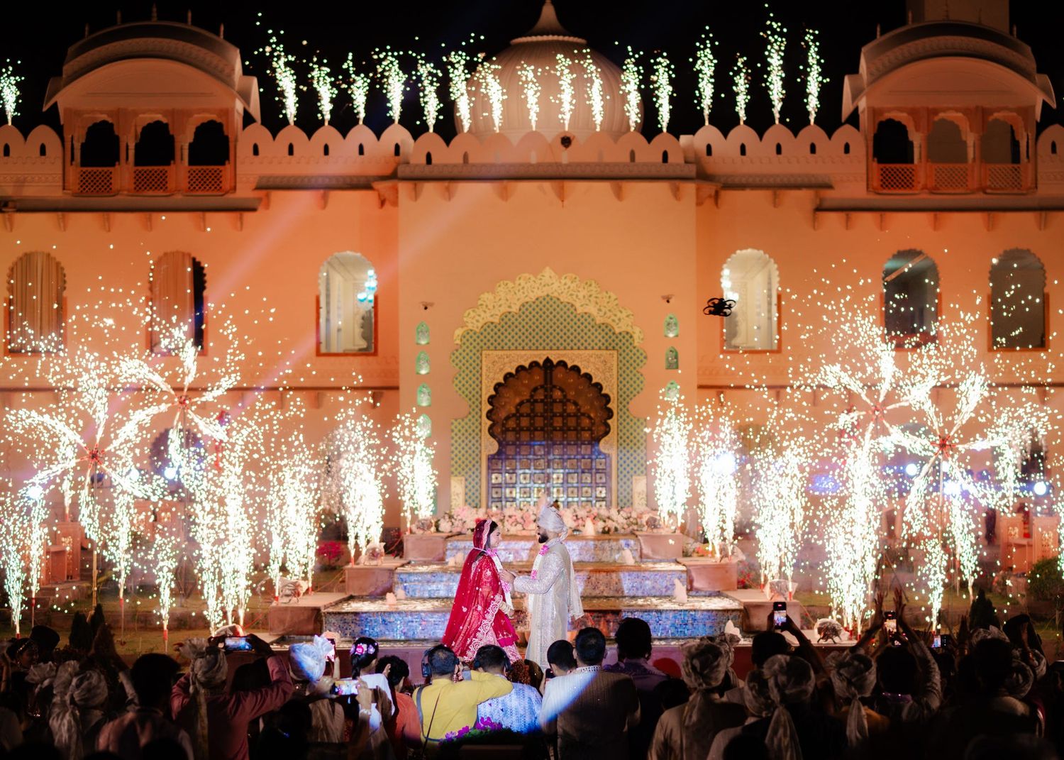 Spectacular Indian wedding ceremony with fireworks and floral light displays at an ornate palace venue.