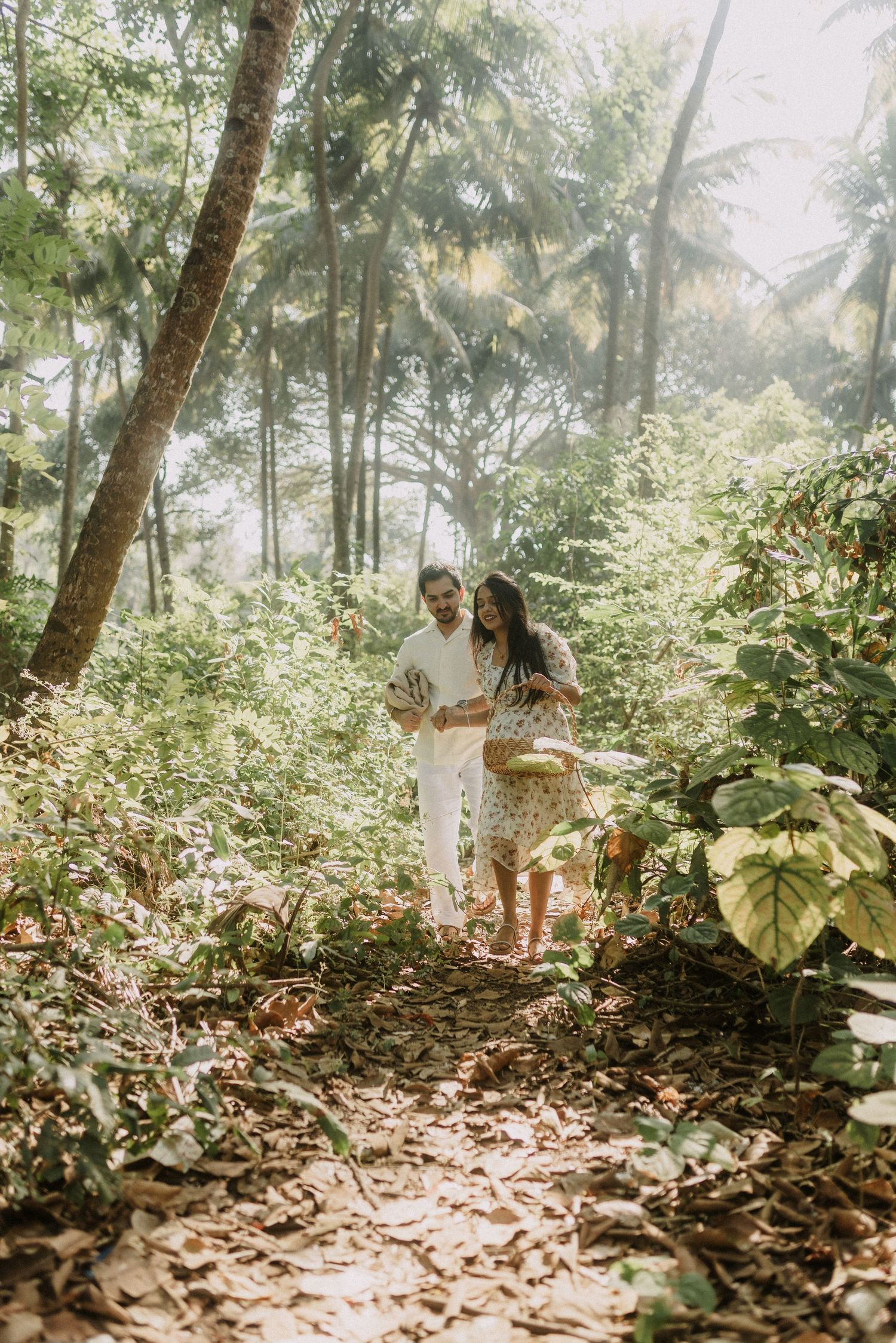 Pre wedding couple walking through a lush tropical forest in Goa with sunlight filtering through palm trees, photographed by Studio RDP