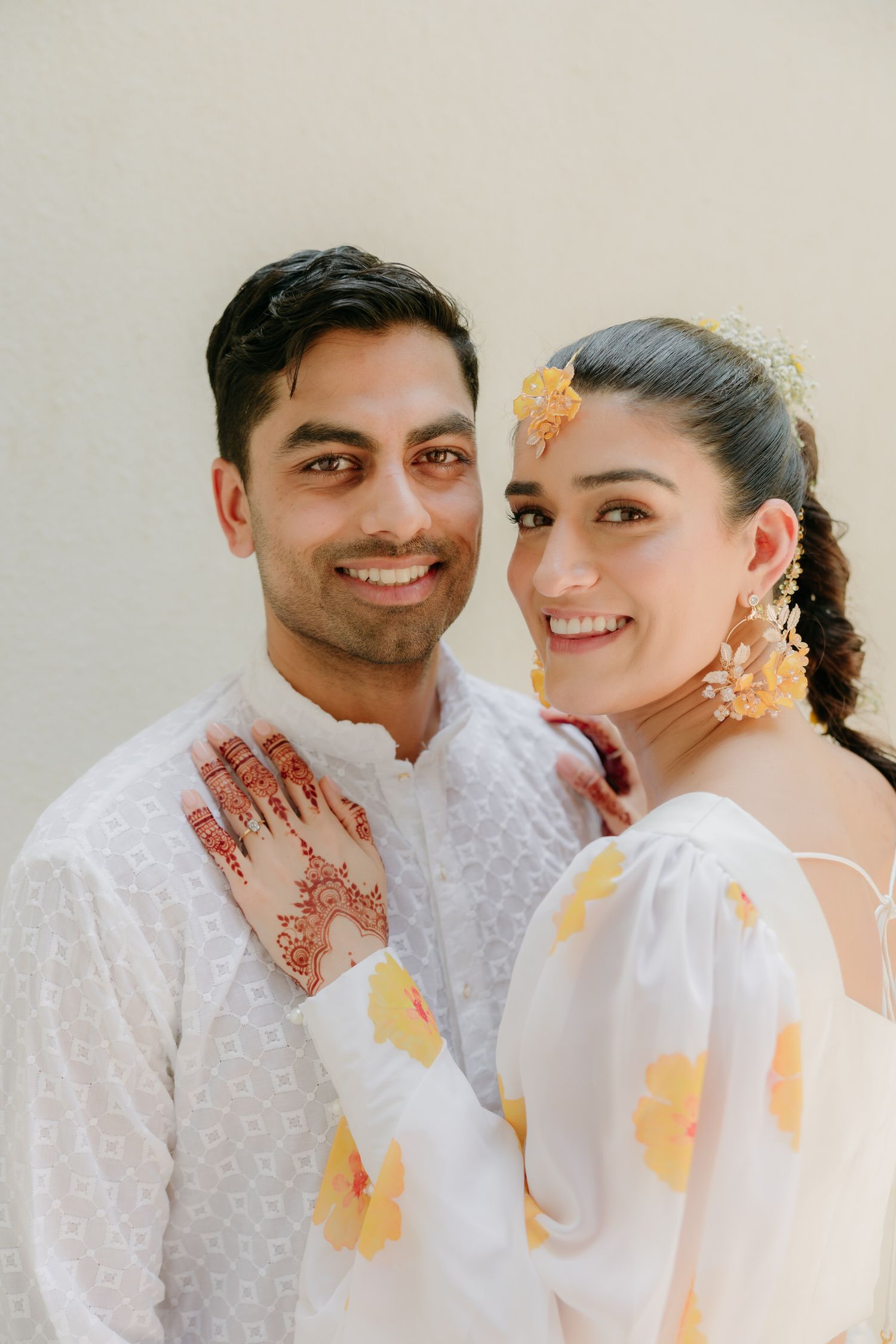 A couple in matching white outfits and traditional henna designs share romantic moments in a photo series.