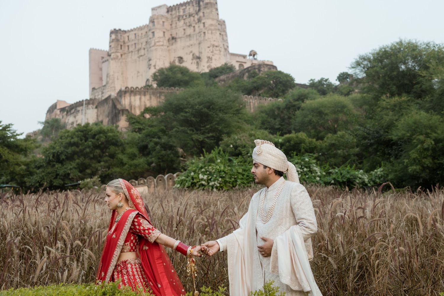 A series of wedding photos in front of a historic castle with traditional Indian attire and decor.