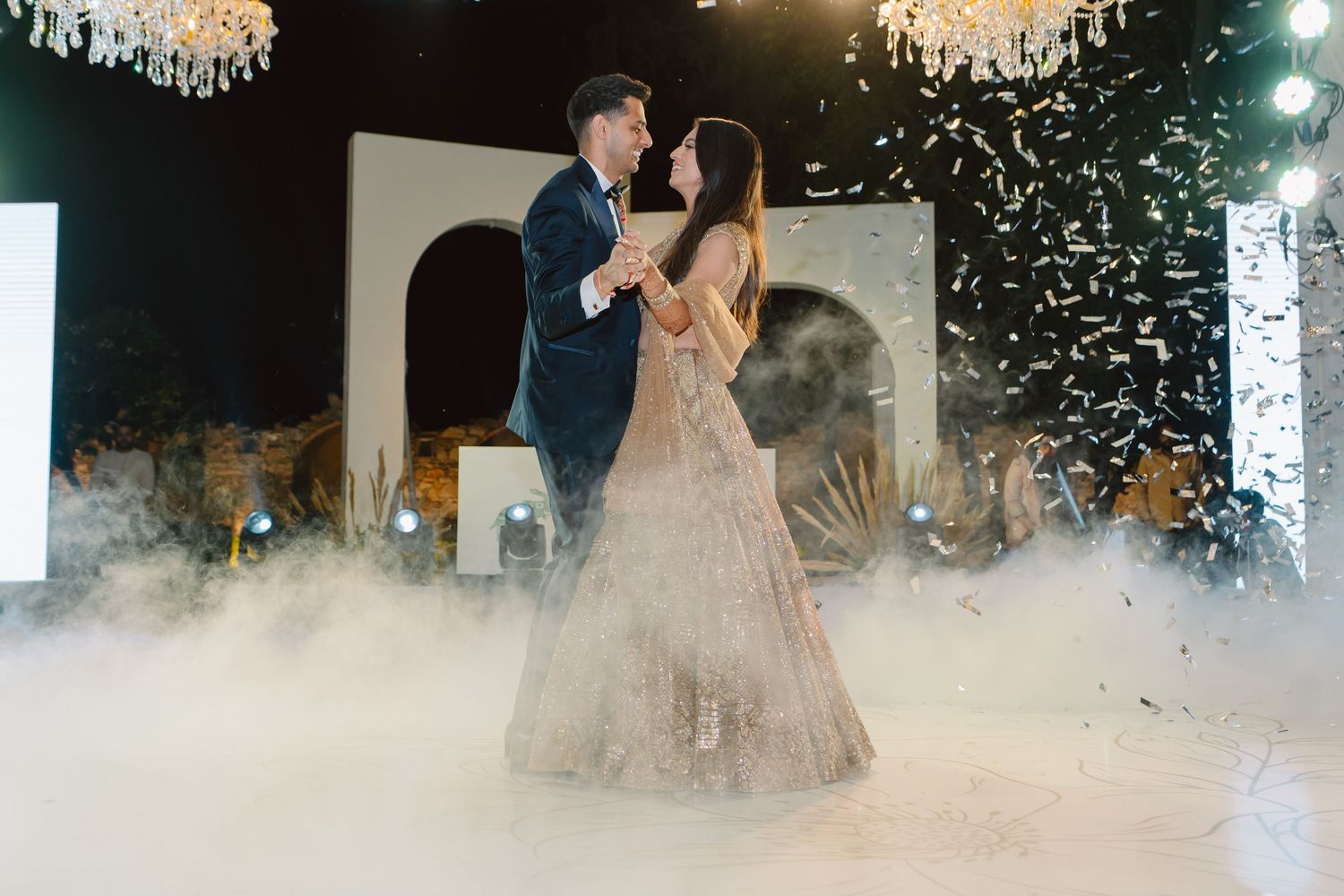 Wedding reception dance floor filled with fog effects and chandelier lighting.