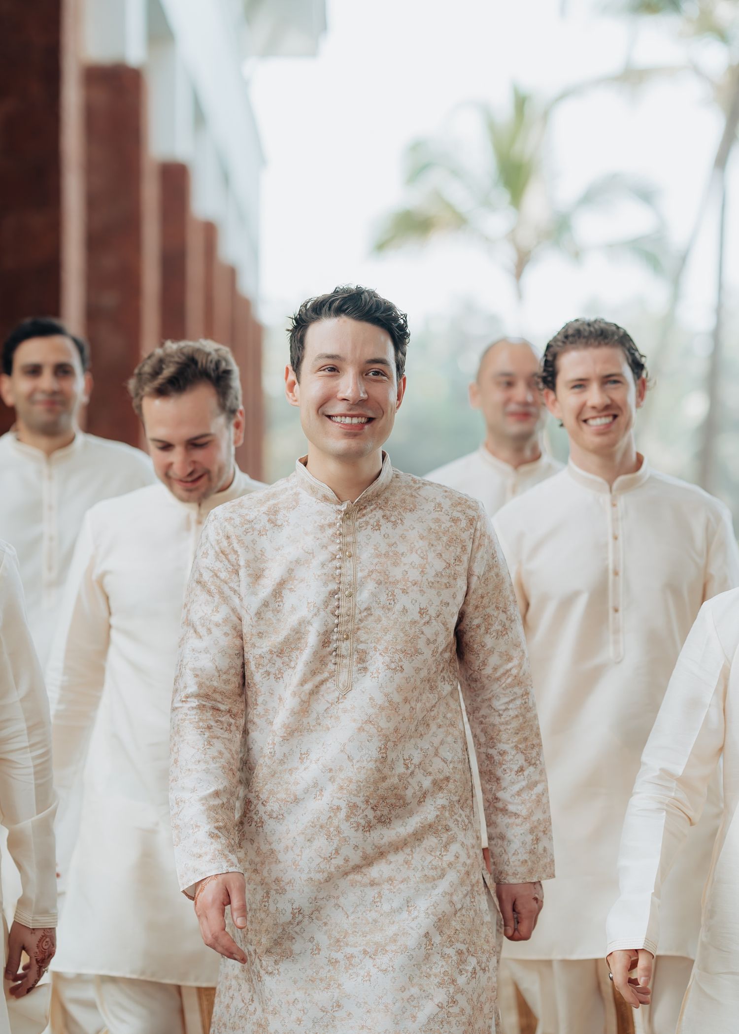 Wedding party members in traditional cream-colored South Asian formal wear standing in a line.