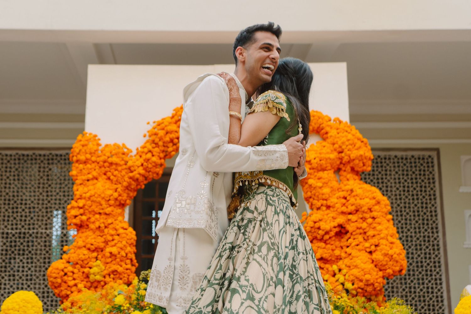 Joyful wedding celebration with vibrant orange marigold flower decorations and traditional yellow attire.