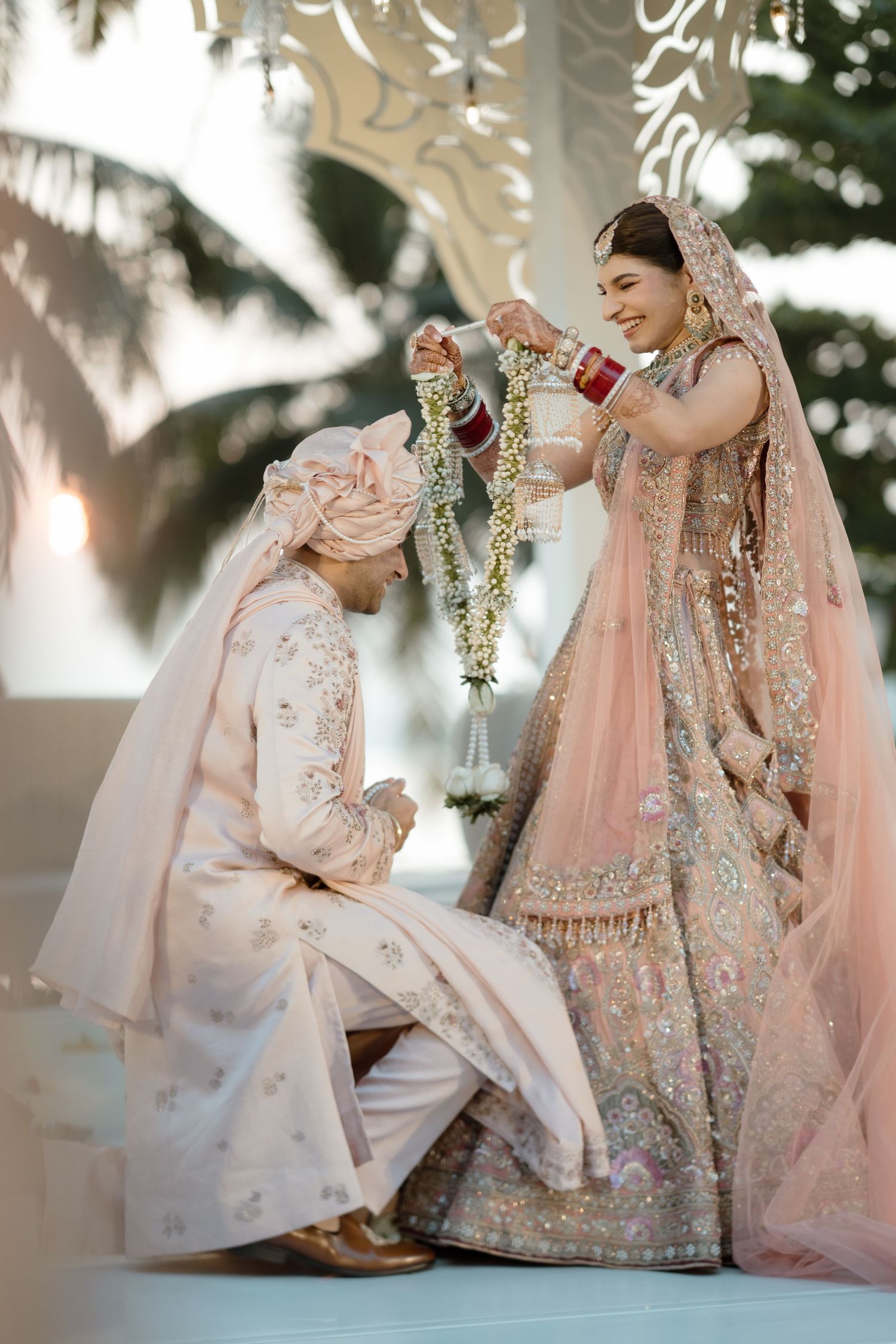 Traditional Indian wedding couple in pastel pink and white outfits posing elegantly during their ceremony.
