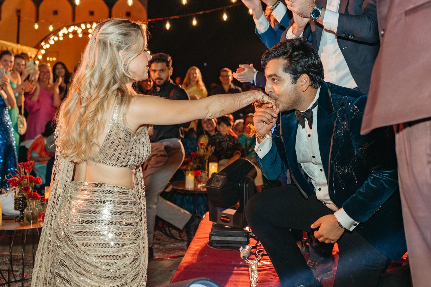 Guests dancing and celebrating at an evening wedding reception with warm lighting.