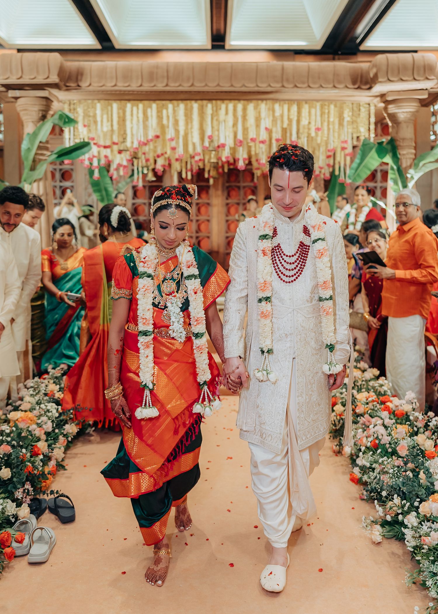 Wedding procession with guests in colorful traditional attire walking through a decorated venue.
