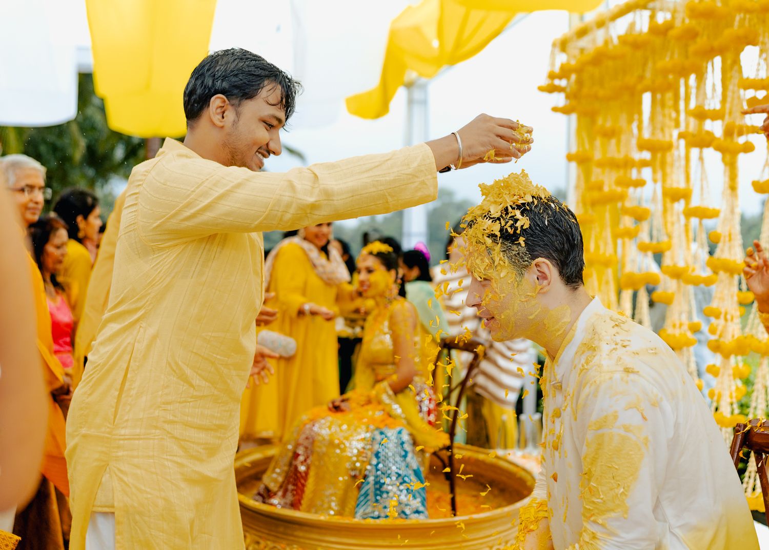 Yellow turmeric powder fills the air during a festive Indian pre-wedding celebration.