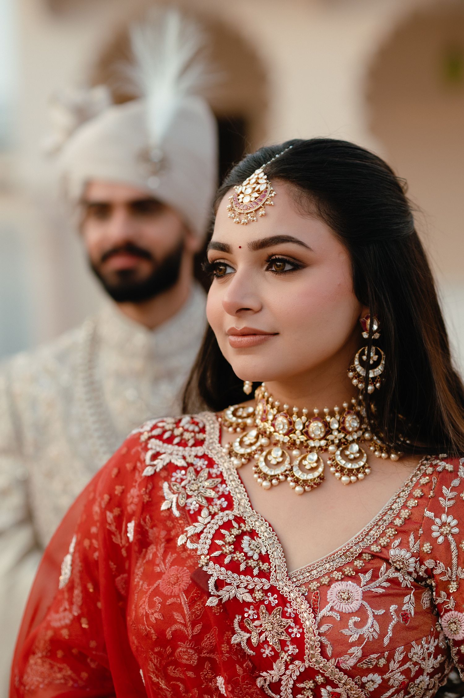 Close-up of Indian bride in red lehenga wearing elaborate gold kundan bridal jewelry set.
