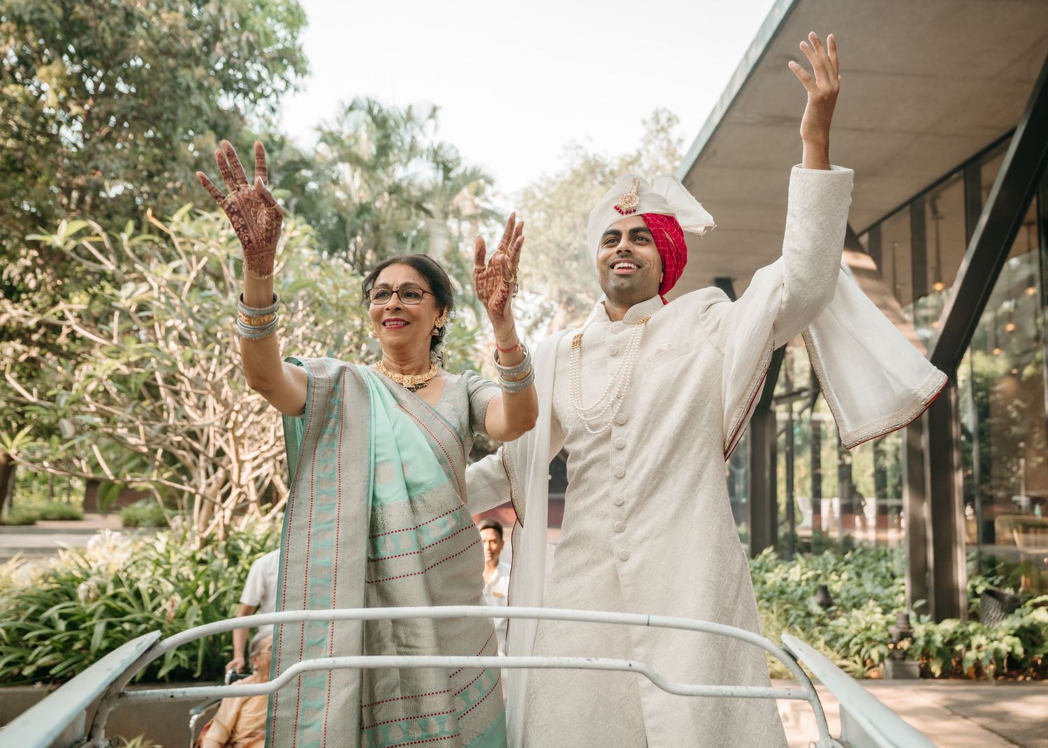 Group of wedding guests dancing joyfully in a garden reception venue under natural lighting.