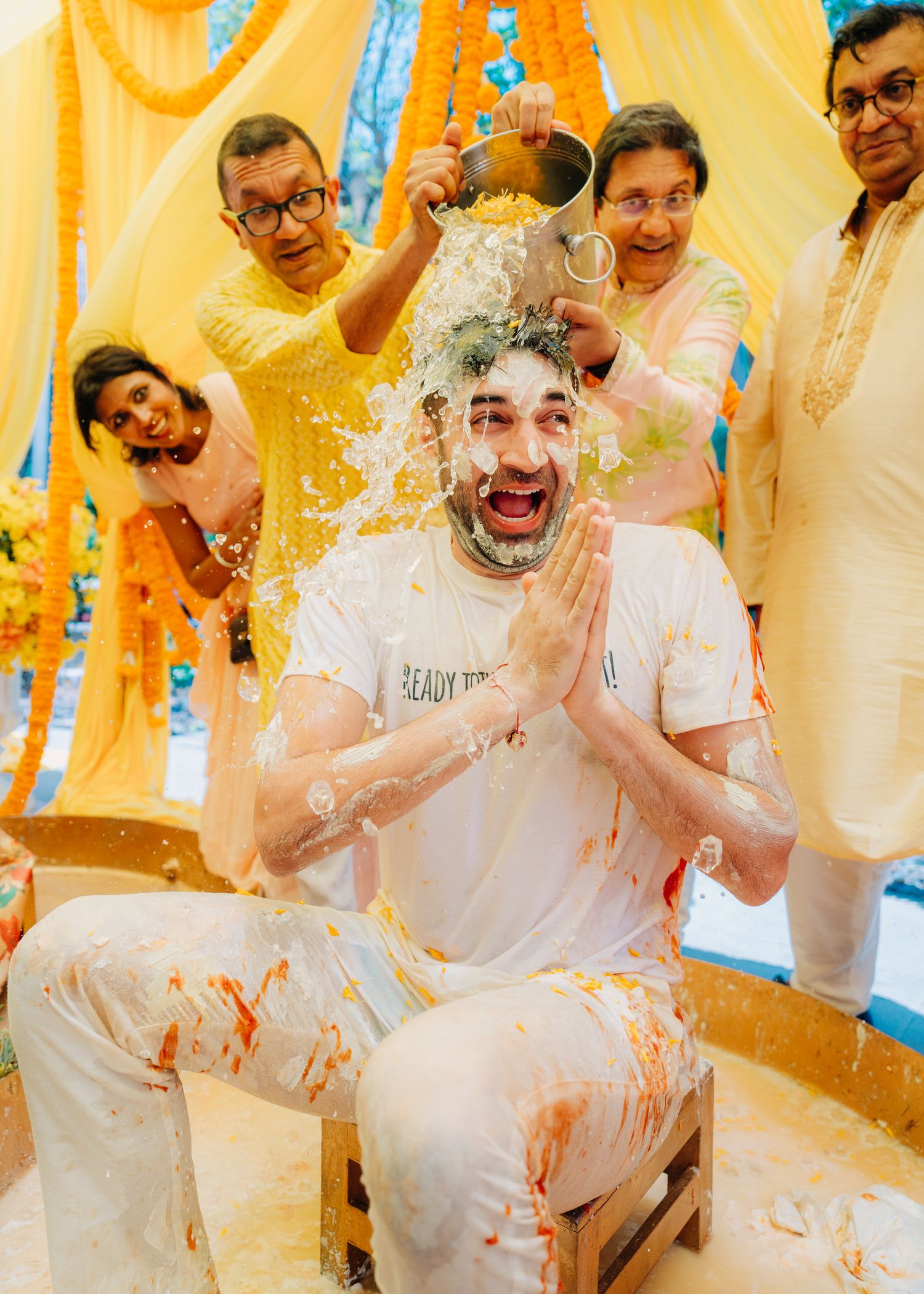 A festive celebration with people in yellow outfits throwing colorful powder during a joyful Holi festival gathering.