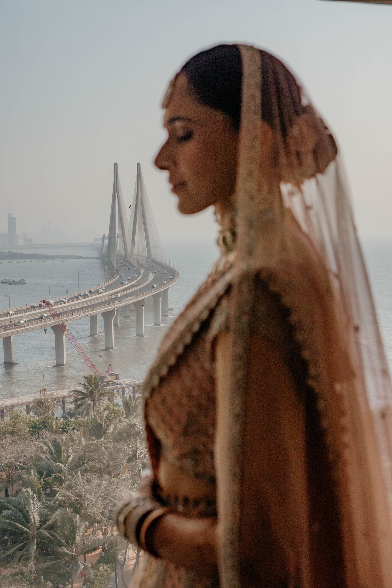 Scenic wedding photos feature a bride in a veil against the backdrop of Bandra-Worli Sea Link bridge in Mumbai, India.