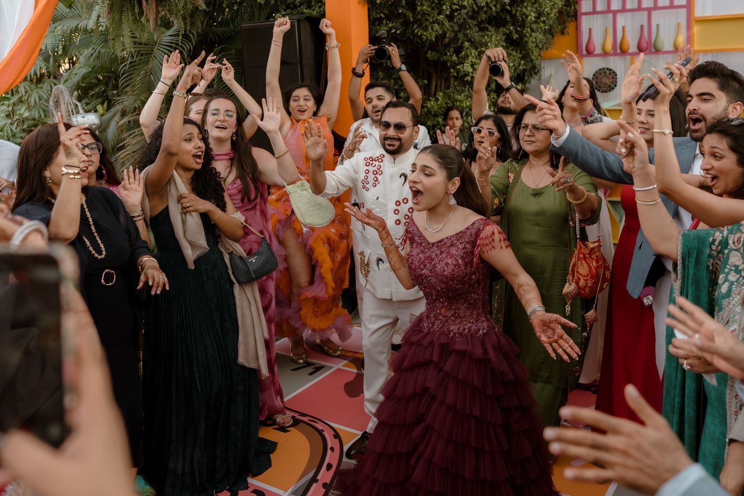 Wedding guests dancing and celebrating together at a lively reception with colorful decor and festive atmosphere.