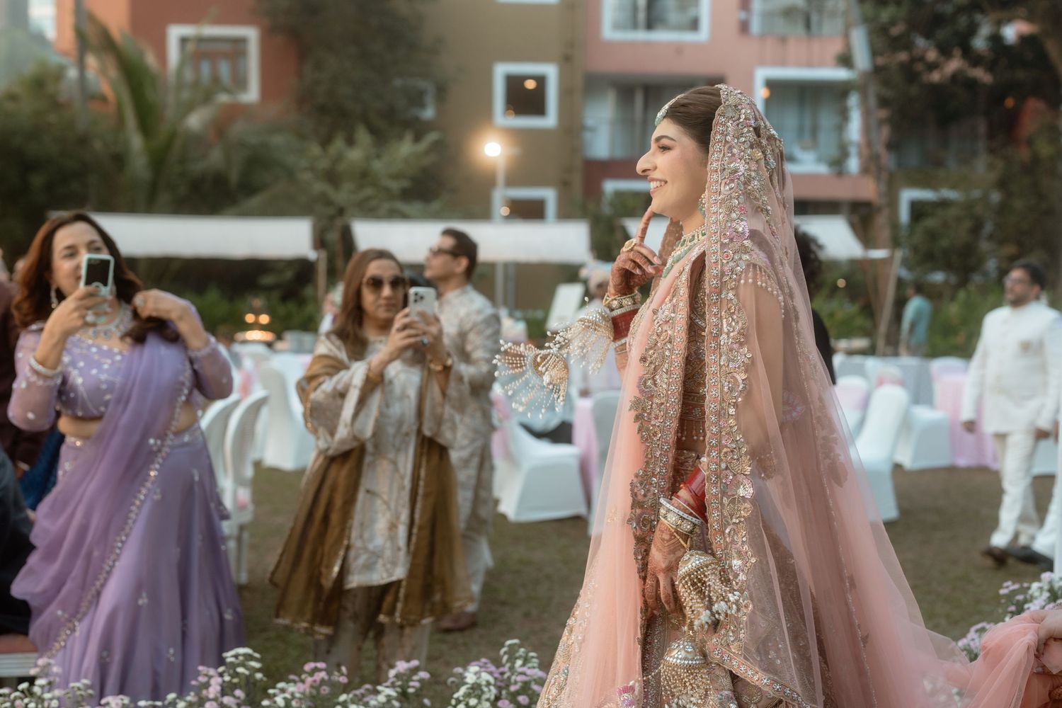 A joyous celebration at an outdoor wedding reception with guests dancing amid flower petals in a garden setting.