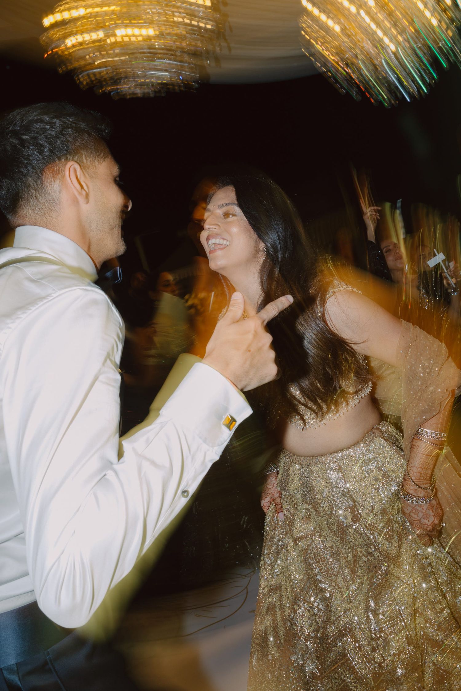 A couple dances under golden chandeliers at their wedding reception.