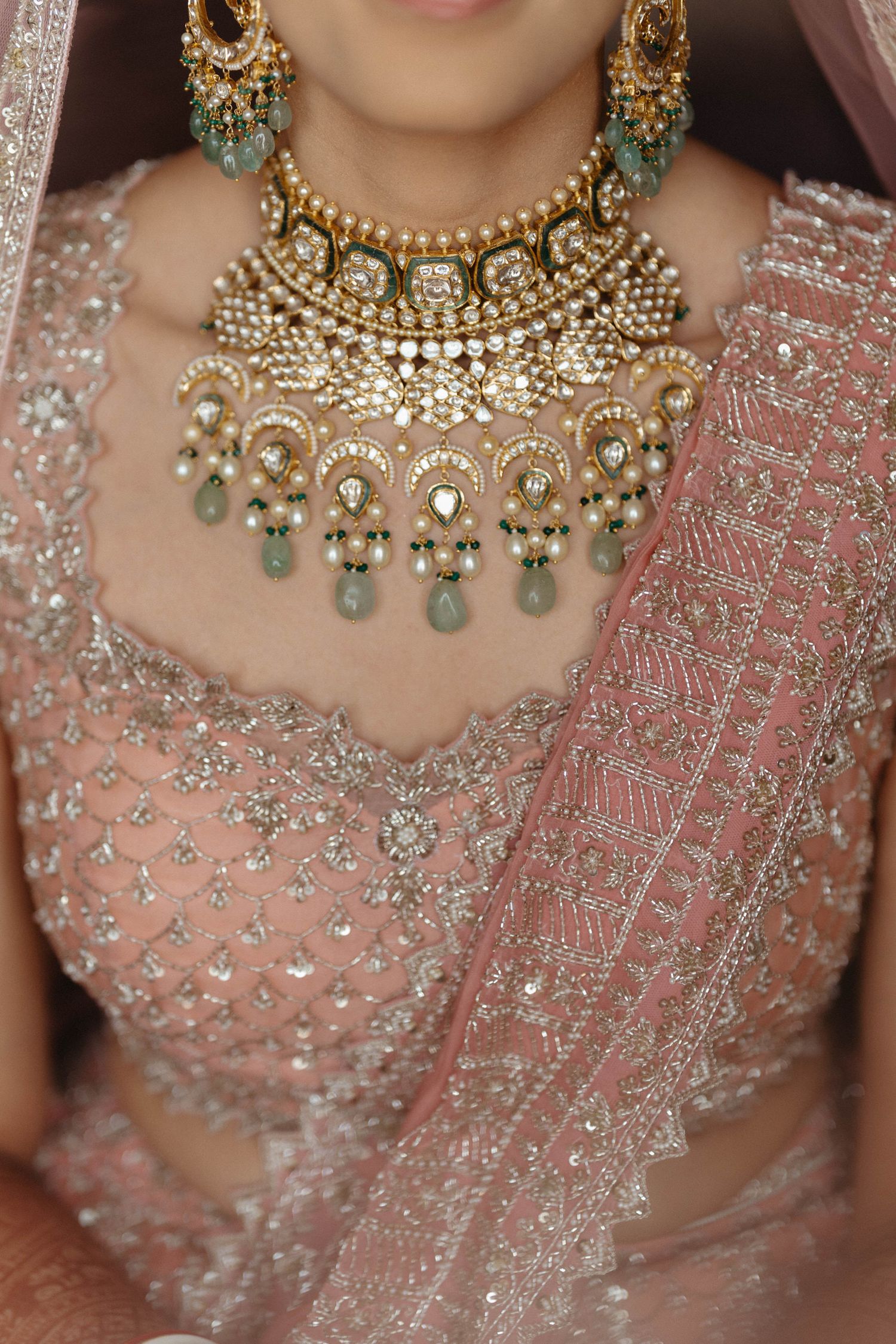 Close-up detail shots of ornate gold and emerald Indian bridal jewelry and pink embroidered saris displaying luxurious craftsmanship.