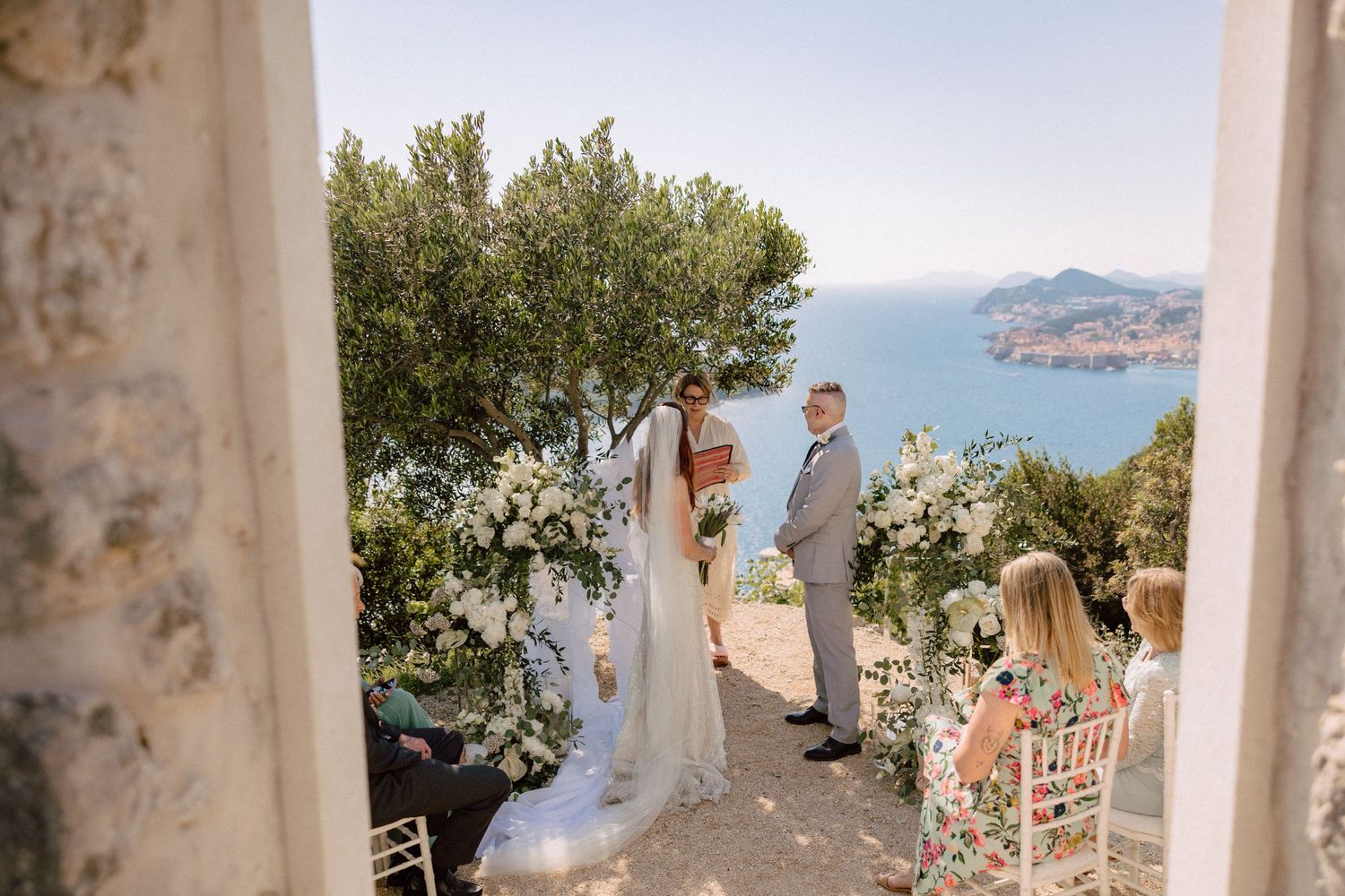 Mediterranean wedding venue with white pillars overlooking coastal scenery.