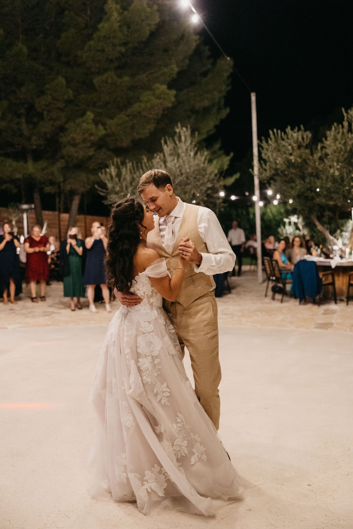 Couples dance together on outdoor illuminated dance floor at night.