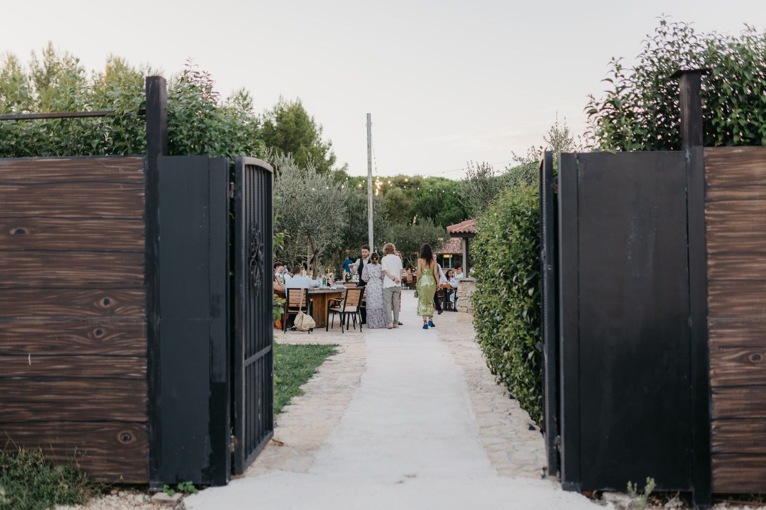 Modern wooden gates lead to an outdoor wedding venue pathway in Italy.