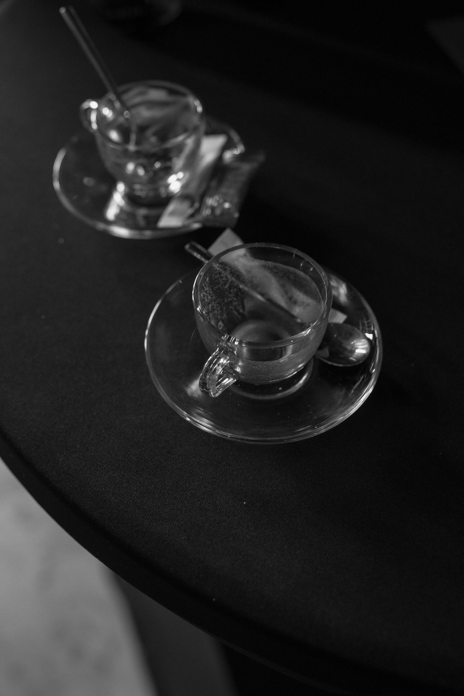 Close-up view of wine glass stems creating abstract shadows on dark surface.