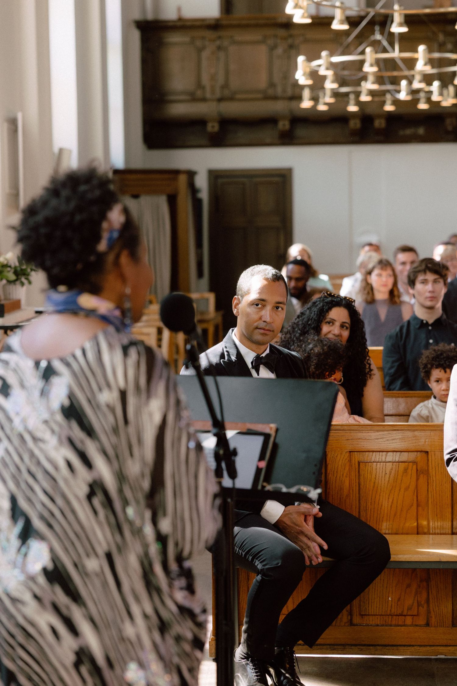 Guests seated in wooden church pews share candid moments during the service.