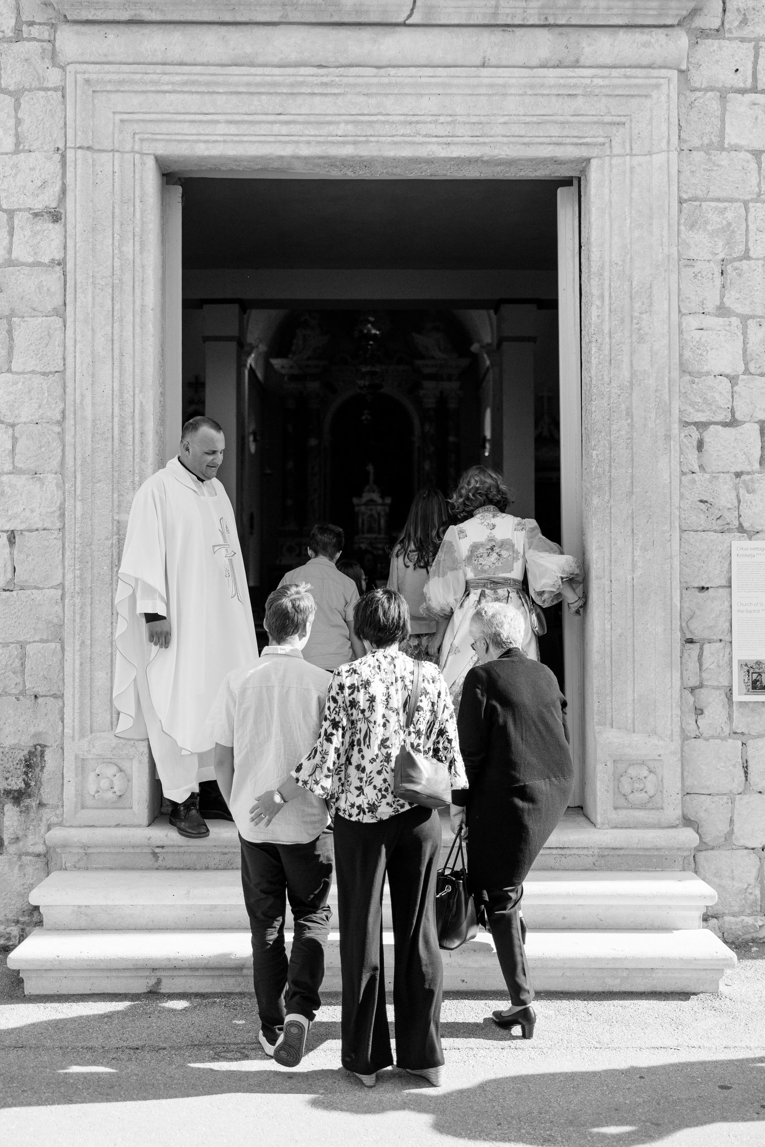 Wedding guests entering a stone building with white columns.