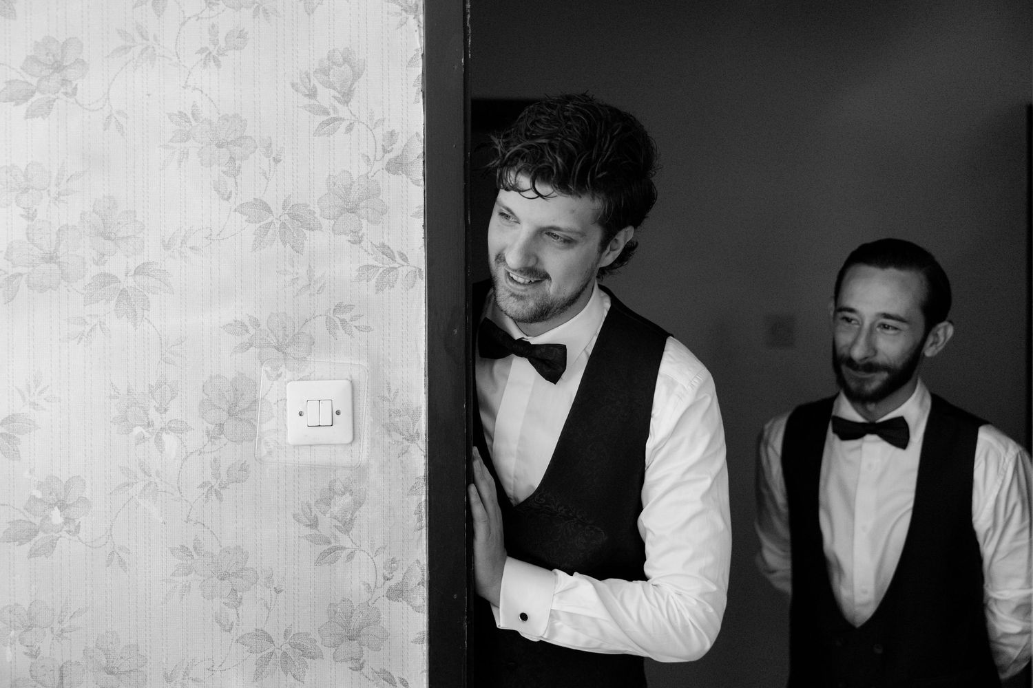 A group of groomsmen in formal black and white attire pose together before a wedding celebration.
