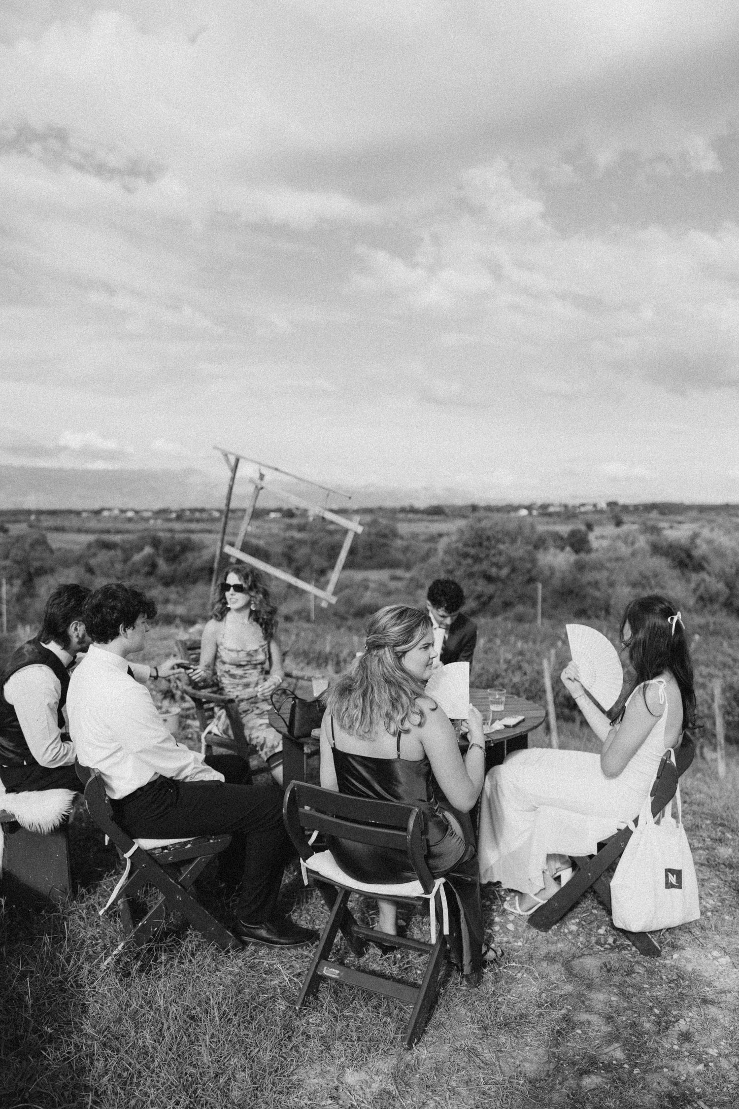 Group relaxing on blankets in a vineyard during a black and white photo session.