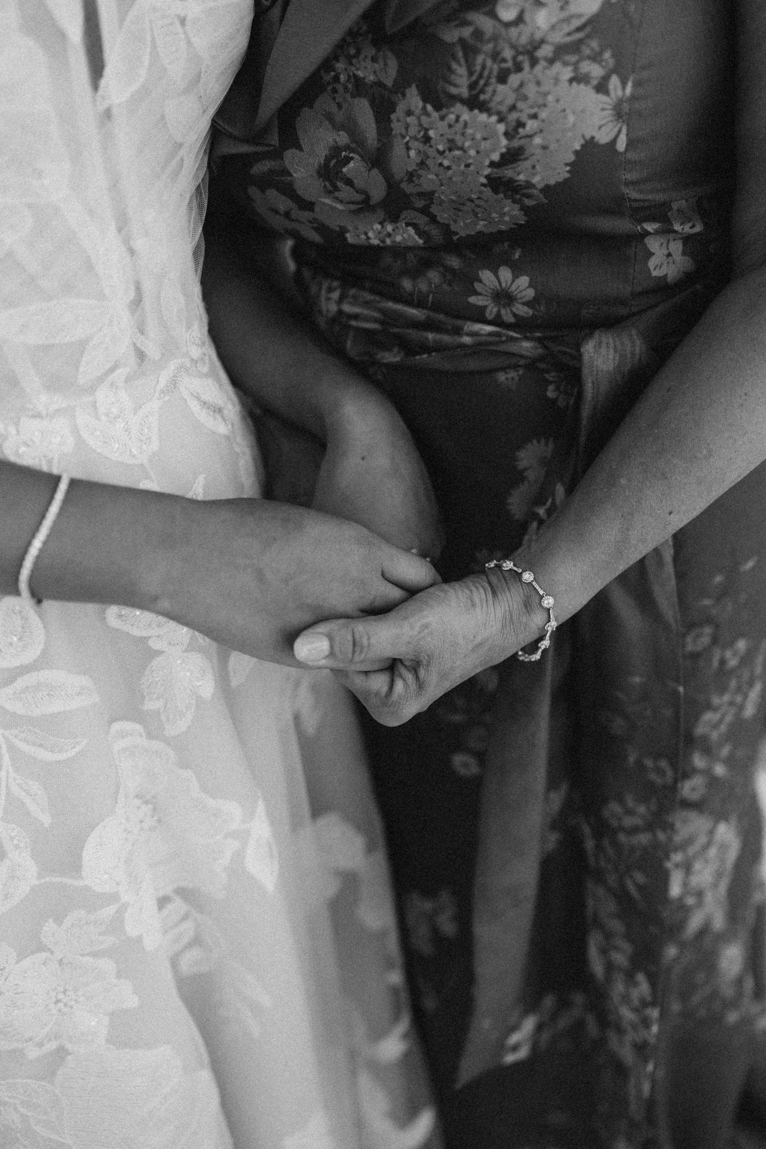 Detailed black and white shot of someone helping adjust the bride's wedding dress.