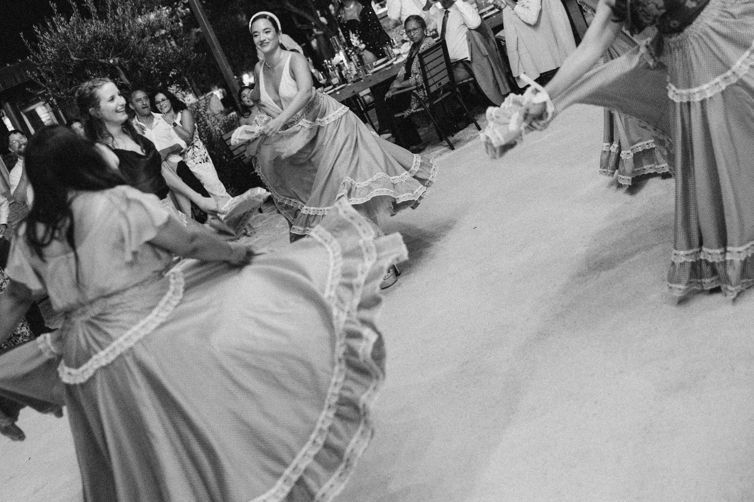 Wedding guests dance in elegant attire at outdoor reception.