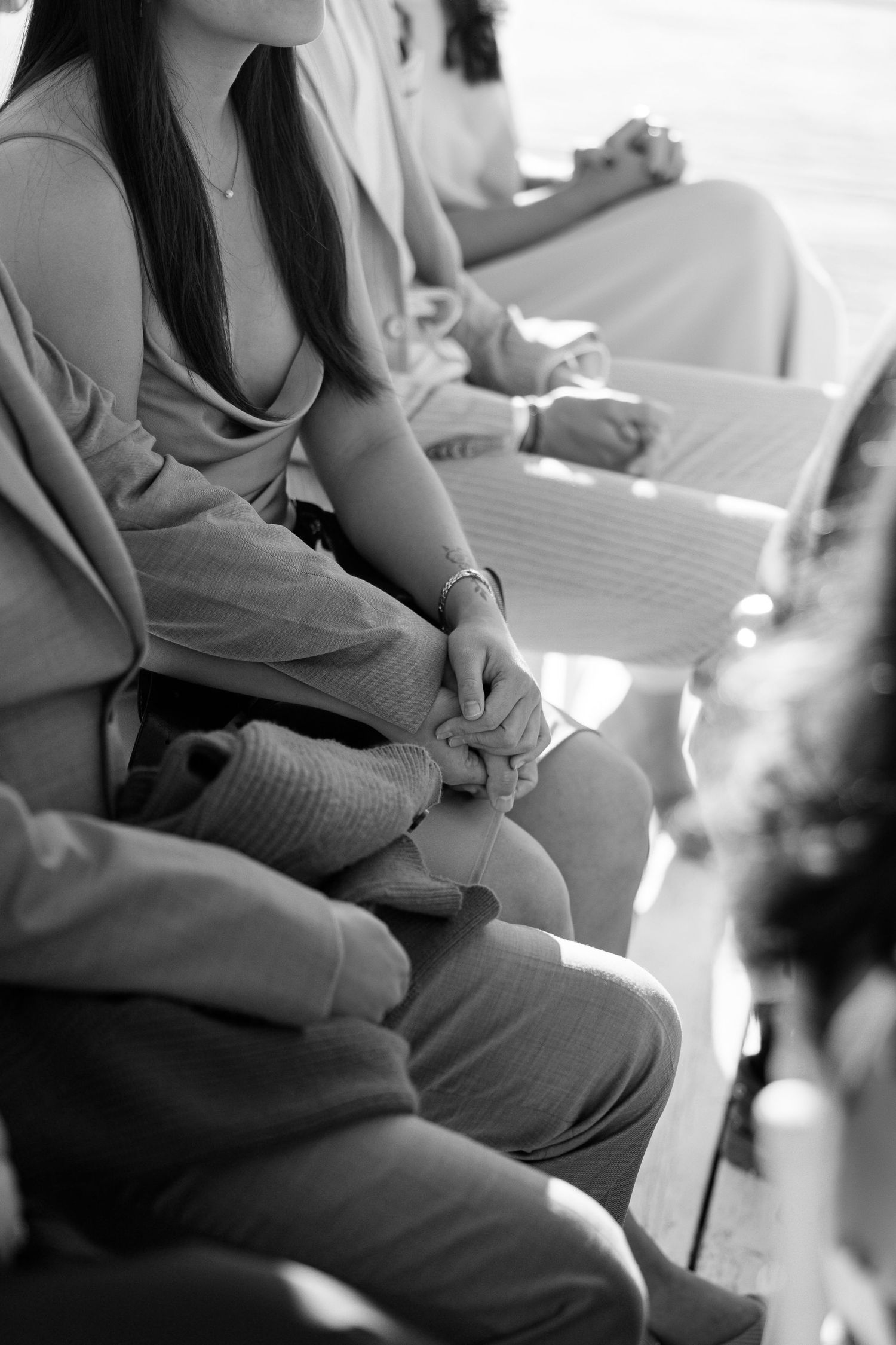 Black and white photo of wedding guests seated on benches holding programs during an outdoor ceremony.