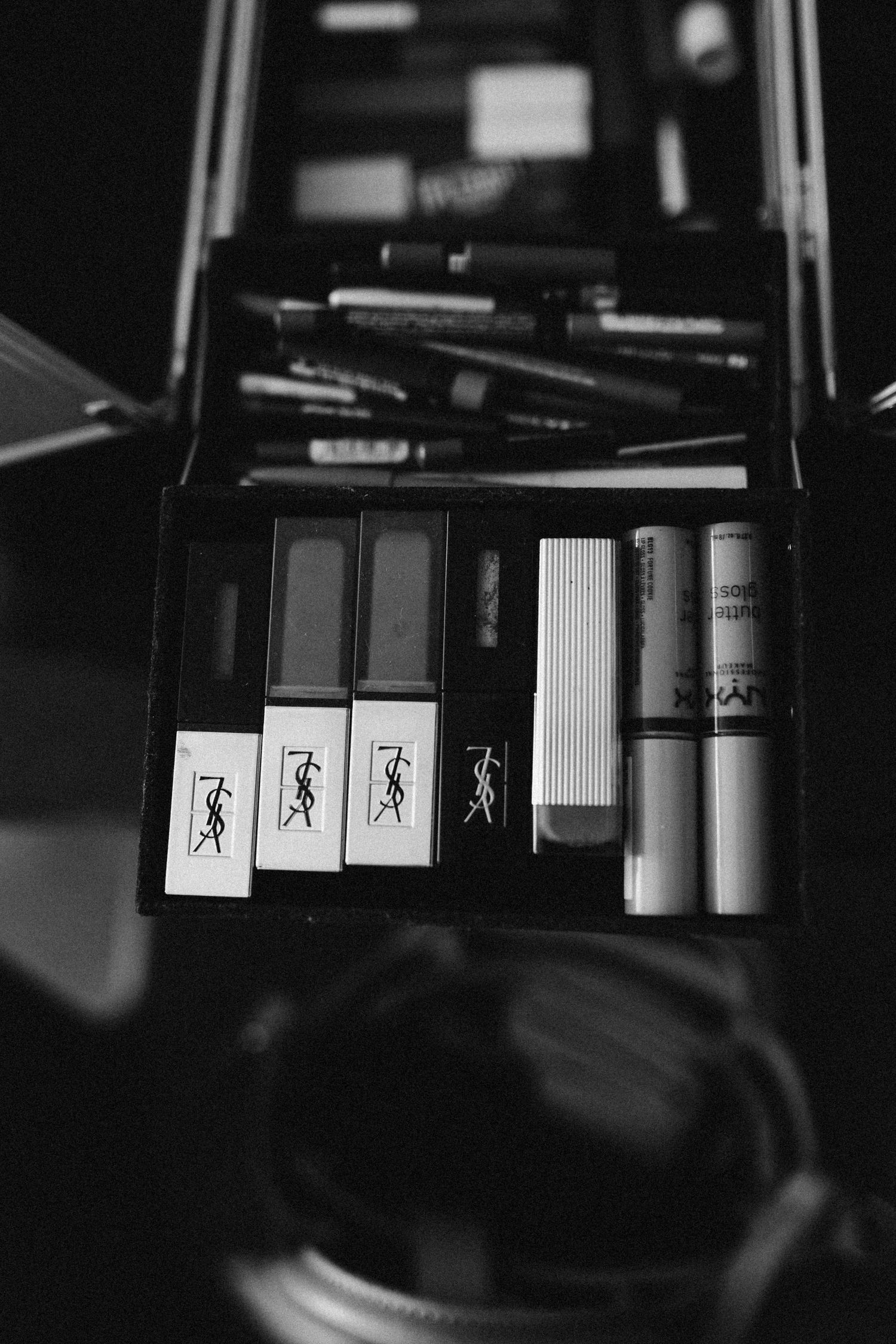 Black and white photo of makeup products and accessories in an open case.